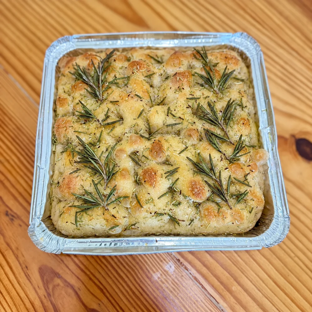 Sourdough focaccia topped with rosemary in a tray